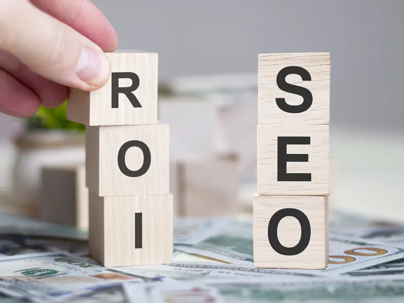 SEO ROI számítás szemléltetése: fa kockákon a SEO és a ROI feliratok, pénzügyi megtérülés és keresőoptimalizálás kapcsolatának vizuális ábrázolása
