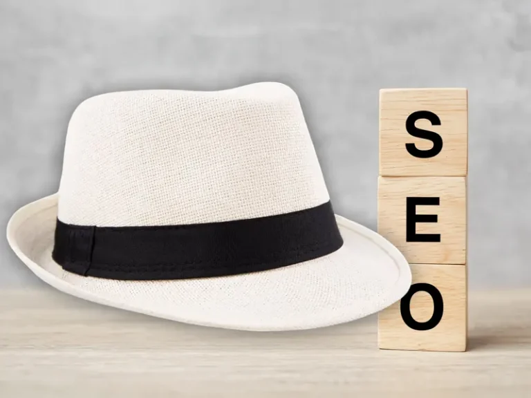 White Hat SEO szemléletet jelképező fehér kalap fa kockákra írt SEO felirat mellett.