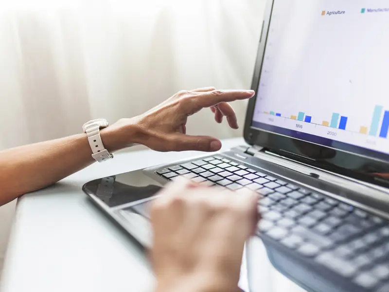 Keresőoptimalizálási teljesítményt elemző szakember laptopon megjelenő grafikonokat vizsgál, amelyek a weboldal átkattintási arányának és organikus forgalmának alakulását mutatják